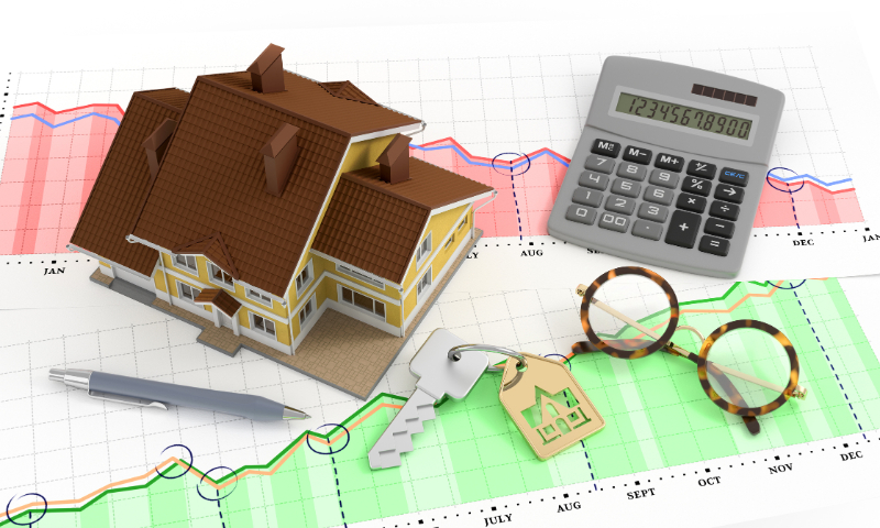 miniature house, calculator and key on graph
